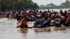 La caravana de migrantes cruza a pie el río que separa a Guatemala de México