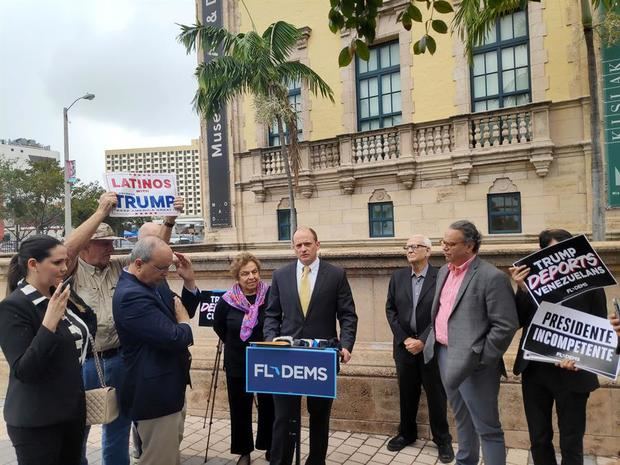 Una persona alza una pancarta que dice 'Latinos for Trump' frente al ex subsecretario adjunto de Defensa para el Hemisferio Occidental, Frank Mora; la congresista demócrata Donna Shalala; el senador estatal, José Javier Rodríguez, y el abogado y político, Leopoldo Martínez Nucete, durante una rueda de prensa este jueves, a los pies de la Torre de la Libertad en Miami, Florida (EE.UU.).