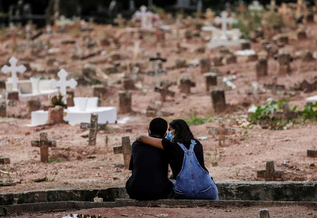Una pareja llora a una mujer víctima de la covid-19 en un cementerio de Río de Janeiro.