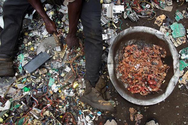 Un hombre rescata hilos de cobre de entre restos de aparatos tecnológicos en un vertedero.