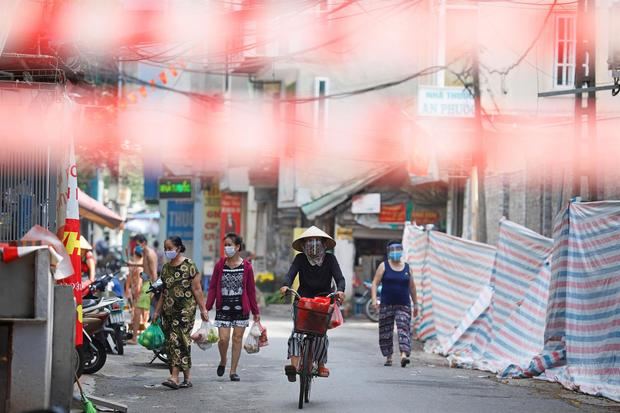 Una mujer circula en bicicleta en un área en cuarentena en Hanoi, Vietnam.