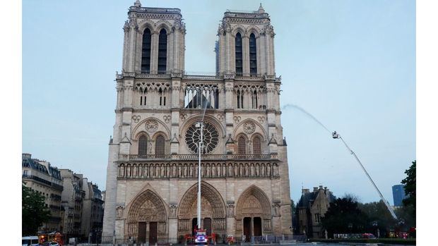 Los miembros de la brigada de bomberos de París rocían agua sobre la fachada de la catedral de Notre Dame este lunes, en Paris (Francia).