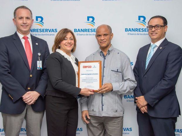 La directora general de Negocios Electrónicos de Banreservas, Antonia Subero; el director de Canales Alternos, José Cueli, y Fidias Brache, gerente de la División Pymes, entregan una placa de reconocimiento a Andrés García, propietario del Centro Copiado La Escalera, ubicado en el Distrito Nacional.