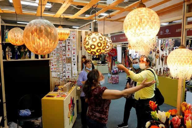 Un grupo de mujeres observa lámparas en uno de los pabellones de la feria Expoartesanías, este 7 de diciembre de 2021, en Bogotá, Colombia.