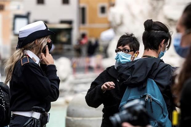 Un policía italiano vigila que los visitantes de la Fontana de Trevi, en Roma, llevan mascarilla.