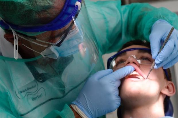 Un dentista trabaja ataviado con las medidas de seguridad impuestas por la pandemia del coronavirus. 