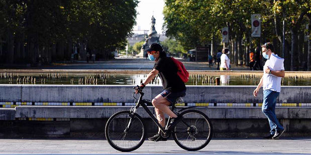 Un hombre circula en bicicleta y con mascarilla por el centro de la ciudad de Valladolid (España) donde este viernes las temperaturas superarán los 35 grados centígrados. 