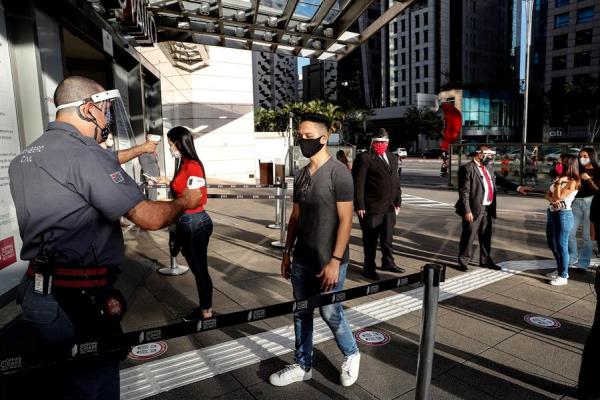 Un funcionario mide la temperatura de los clientes que ingresan a un centro comercial este jueves, en Sao Paulo (Brasil). 