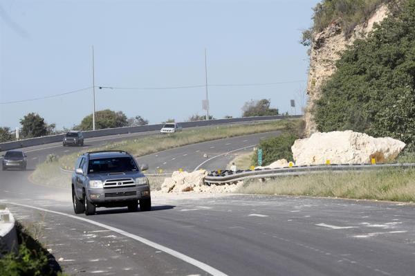 Vehículos pasan junto a las piedras que bloquean una de las calzadas de una carretera afectada tras el sismo registrado este martes, en la entrada de la ciudad de Ponce (Puerto Rico). 