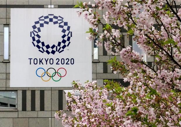 Un cartel con el logotipo de los Juegos Olímpicos de Tokio 2020 junto a un cerezo en flor, en Tokio.