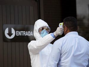 Un funcionario de sanidad toma la temperatura a una persona que ingresa al edificio del Banco Central este miércoles, en Santo Domingo, República Dominicana.