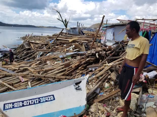 Una foto distribuida por la Oficina del Vicepresidente de Filipinas (OVP) muestra a un aldeano parado junto a los escombros en una aldea costera en la devastada ciudad de General Luna, isla de Siargao, Filipinas, el 19 de diciembre de 2021.