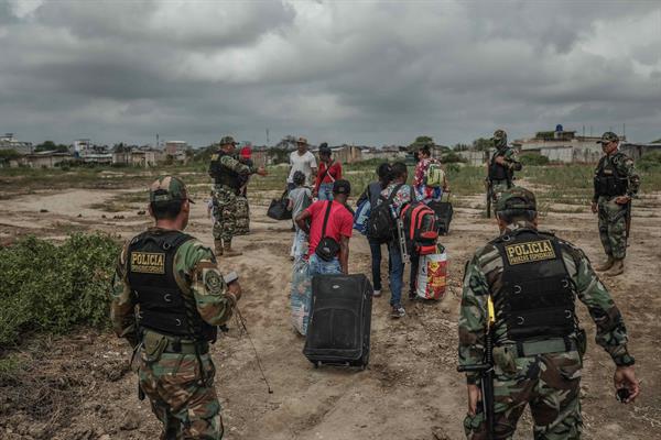 Miembros de la policía de Perú controlan el paso de migrantes venezolanos que intentan cruzar la frontera de Perú por la orilla del río Zarumilla.