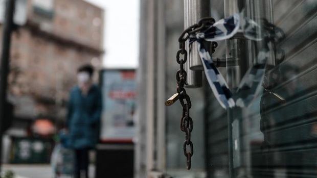 Las cadenas de un comercio cerrado fueron registradas este miércoles, con la silueta de una persoana con tapabocas al fondo, en la capital argentina.