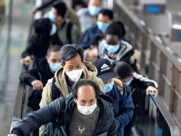 Personas con máscaras suben por una escalera mecánica en la estación de tren de alta velocidad en Guangzhou, provincia de Guangdong, China, el 12 de marzo de 2020.