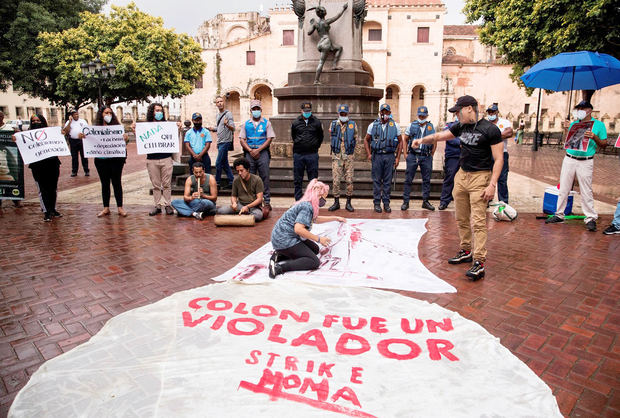 Un grupo de personas protesta junto a una estatua de Cristóbal Colón hoy, día en el que se conmemora el 529 aniversario de la llegada del almirante a América, en Santo Domingo, República Dominicana.