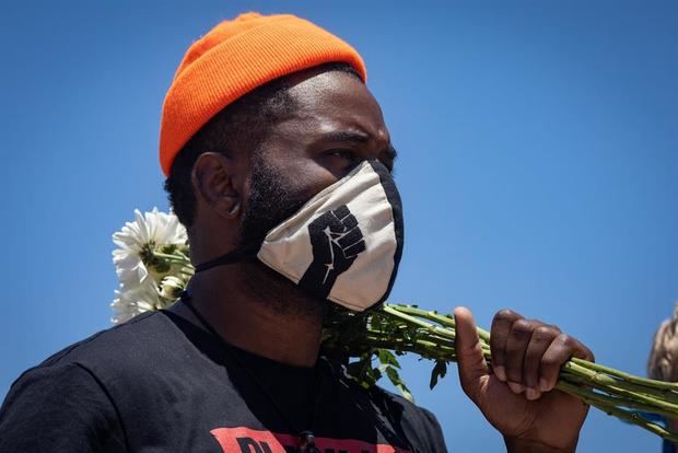 Un hombre sostiene un ramo de flores durante una protesta de 'Black Lives Matter' (Las vidas negras importan), en las afueras de la Universidad del Sur de California en Los Ángeles, EE.UU.