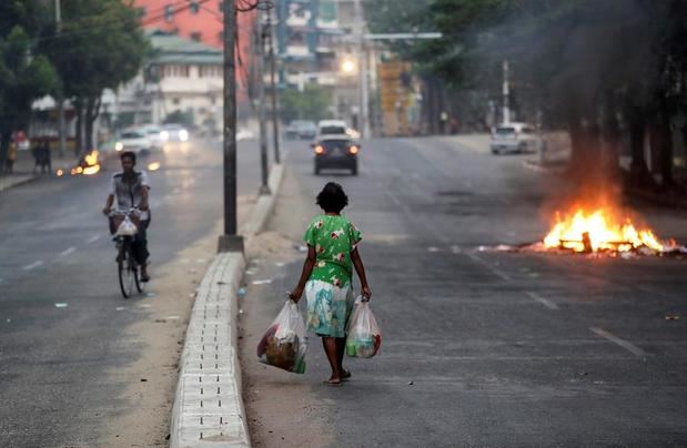 Personas se desplazan por una calle junto a hogueras que simbolizan la resistencia contra el golpe de Estado, este miércoles en Rangún.