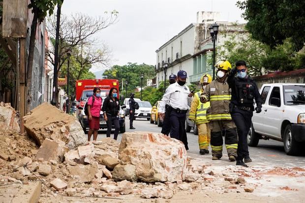 Miembros de la policía y de los bomberos observan los daños causados en una barda derrumbada este martes, en la ciudad de Oaxaca, México.