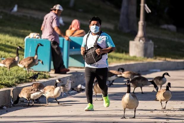 Un hombre corre con un tapabocas en el parque MacArthur en Los Ángeles, EE.UU., el 21 de mayo 2020. 