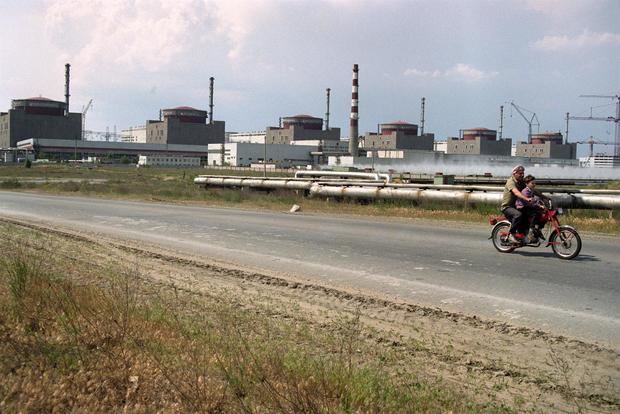 Un hombre con un niño pasa en una moto ante la central nuclear de Zaporozhye (Ucrania), en una foto de archivo.