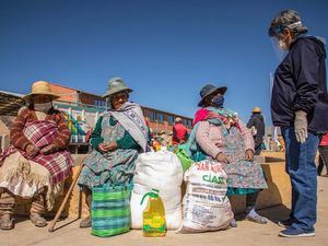 Un representante del Programa Mundial de Alimentos en Bolivia habla con una mujer indígena Uru-Murato sobre el COVID-19 y la buena nutrición.