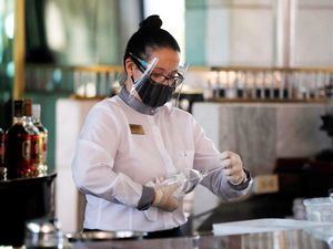 Una trabajadora de un hotel, protegida con máscara y tapabocas como medida preventiva contra el covid-19, limpia una copa el 11 de febrero de 2021, en La Habana, Cuba.