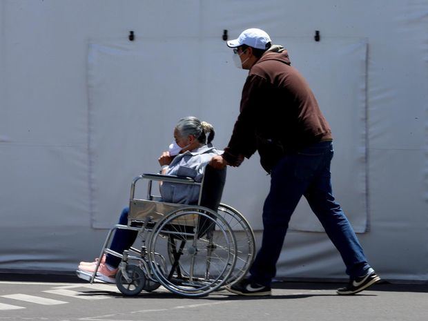 Una persona lleva en silla de ruedas a un familiar en las afueras del Hospital Iess del Sur en Quito, Ecuador.