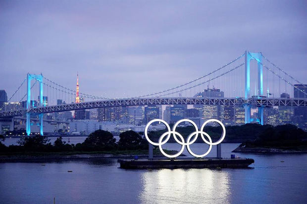 Los aros olímpicos iluminan el agua cerca del Puente del Arco Iris en el Parque Marino de Odiaba, Japón.