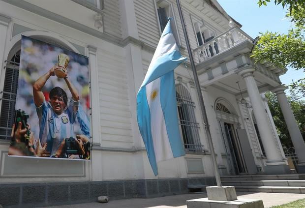 Fotografía de la imagen de Diego Maradona en la embajada de Argentina en La Paz donde rinden homenaje el exfutbolista con un cartel en la fachada.