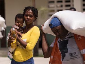 Una mujer recibe una de las raciones alimentarias que entrega el Programa Mundial de Alimentos (WFP) de la ONU, hoy, en Camp Perrin, Haití.