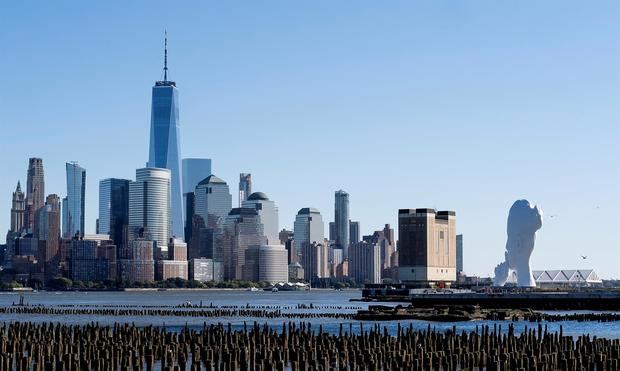 La escultura 'Water's Soul' (d) del artista español Jaume Plensa es vista en el muelle frente a Manhattan en Nueva Jersey (EE.UU.), este 19 de octubre de 2021.