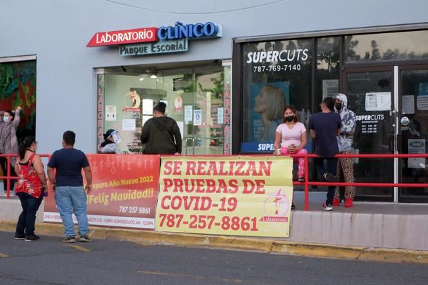 Unas personas hacen hoy fila para hacerse la prueba de covid-19 a las afueras de un laboratorio en San Juan, Puerto Rico.