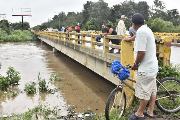 Pobladores observan el aumento del caudal del rio Chamelecón luego de que el gobierna emitiera alerta roja y ordenara evacuar las zonas bajas de la costa norte de Honduras debido al aumento de las lluvias por causa del huracán Julia, hoy en La Lima, Honduras.