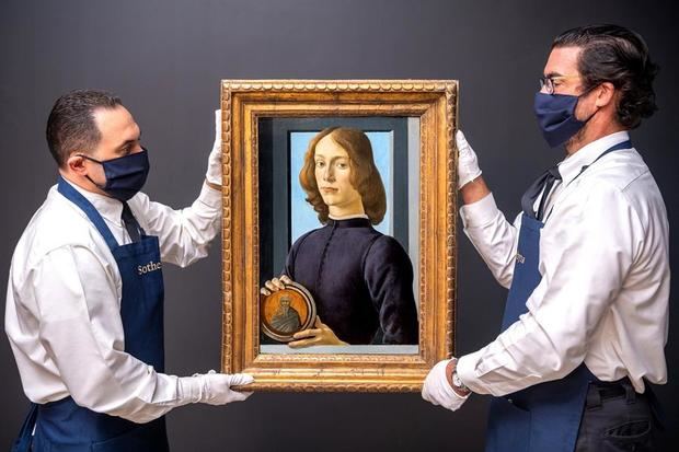 Fotografía cedida por Sotheby's donde aparecen dos de sus empleados mientras disponen la obra 'Young Man Holding a Roundel' (Hombre joven sujetando un medallón) pintada por el italiano Sandro Botticelli.