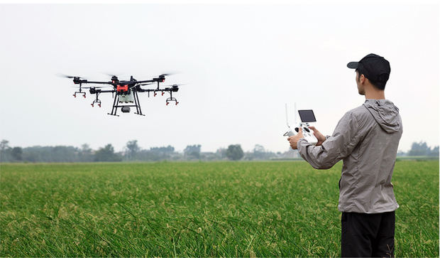 Un agricultor pilota con su teléfono móvil un dron preparado para tareas agrícolas.