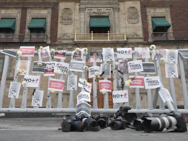 Fotografía de carteles, flores, retratos y cámaras fotográficas en el suelo como acto de protesta por los asesinatos a periodistas, hoy al exterior de Palacio Nacional de Ciudad de México, México.