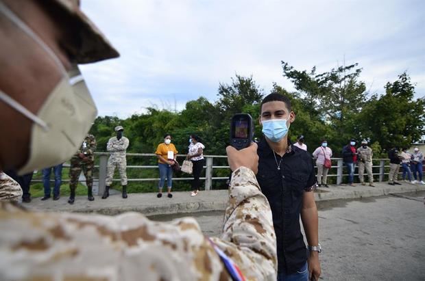 Integrantes de las Fuerzas Militares Dominicanas controlan la temperatura a ciudadanos haitianos que ingresan hoy, al tradicional mercado binacional de la ciudad fronteriza de Dajabón, República Dominicana.
