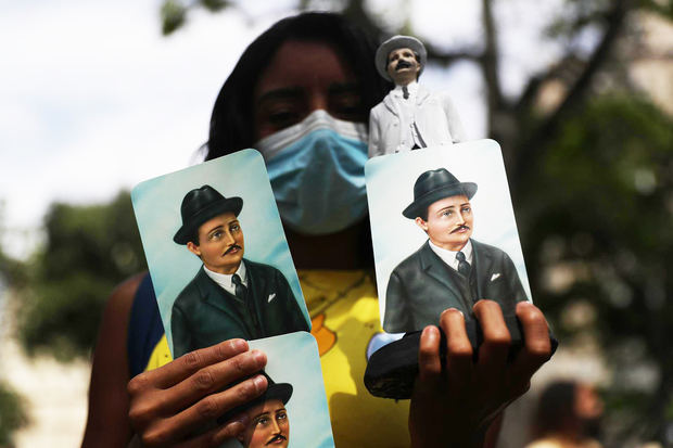 Una mujer sostiene hoy imágenes de José Gregorio Hernández con motivo de su ceremonia de beatificación, frente a la iglesia de Nuestra Señora de la Candelaria, en Caracas, Venezuela.