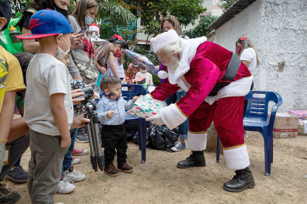 Un hombre vestido de Santa Claus entrega de regalos de 'Un Juguete, una buena noticia' hoy, en Caracas, Venezuela.