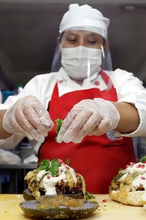 Una mujer prepara una hamburguesa que lleva los ingredientes del tradicional chile en nogada, el 17 de julio de 2020, en un restaurante de Puebla (México). 