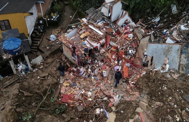 Fotografía tomada con un drone que muestra a dos hombres junto a una vivienda destrozada en medio de la destrucción tras las fuertes lluvias del martes en el Morro de la Oficina, el 18 de febrero de 2022, en la ciudad de Petrópolis, estado de Rio de Janeiro, Brasil.
