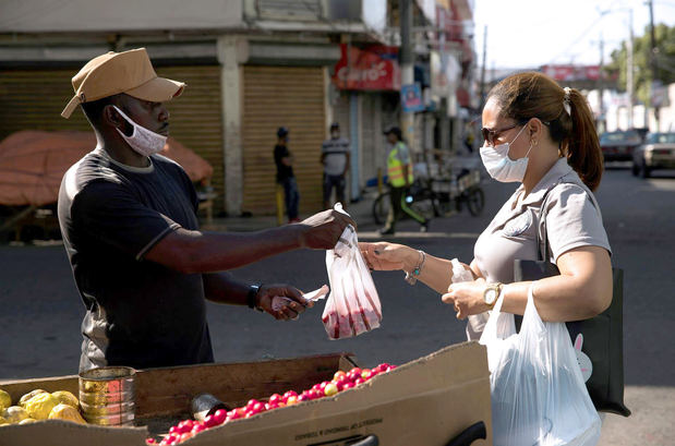 Un haitiano vende cerezas a una mujer, en una fotografía de archivo.