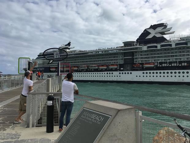 Dos personas saludan hacia un crucero durante su salida del puerto de Miami, Florida, EE.UU. 
