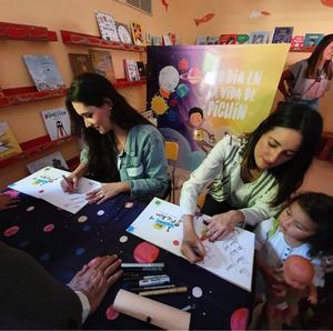 Amelia Vega y Taina Almodóvar firmando libros en la presentación del libro.