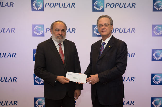 En nombre de la Fundación Popular, el señor Manuel A. Grullón, presidente del Banco Popular Dominicano y presidente del Grupo Popular, la casa matriz, realiza la entrega del aporte al ingeniero Francisco Pagán, director general de la Oficina de Ingenieros Supervisores de las Obras del Estado (OISOE).