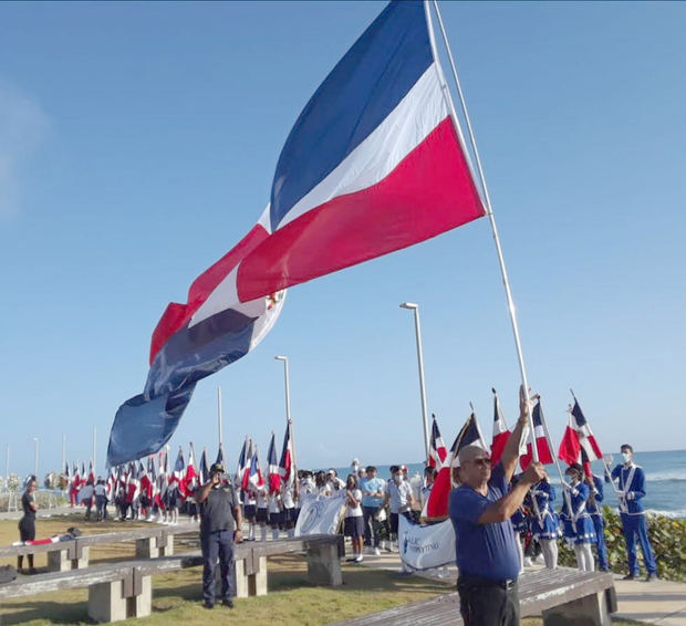 Estudiantes y autoridades enarbolan la Bandera Nacional.