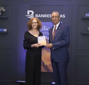 Victoria Díaz Bonelly, hija de Virgilio Díaz Grullón, recibe un ejemplar del libro que reúne los mejores cuentos de su padre. El administrador general de Banreservas, Simón Lizardo Mézquita,  le hace entrega, en el Centro Cultural de la institución financiera. (Foto:Cortesía).