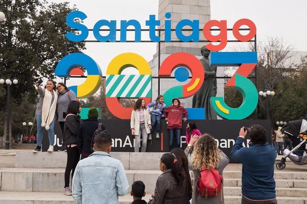 Un grupo de personas se toma fotografías este sábado frente a un cartel que anuncia la celebración de los juegos Panamericanos y Parapanamericanos 2023, en Santiago (Chile) durante el lanzamiento oficial de la capital como sede. 