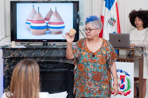 Xiomarita Pérez mostrando un trompo artesanal, durante conferencia 'A brincar la tablita con Xiomarita'.